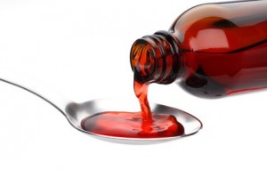 Bottle pouring Medicine Syrup in Spoon